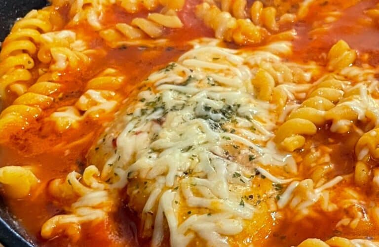 Fusilli pasta and Parmesan cheese added to the skillet with tomato chicken
