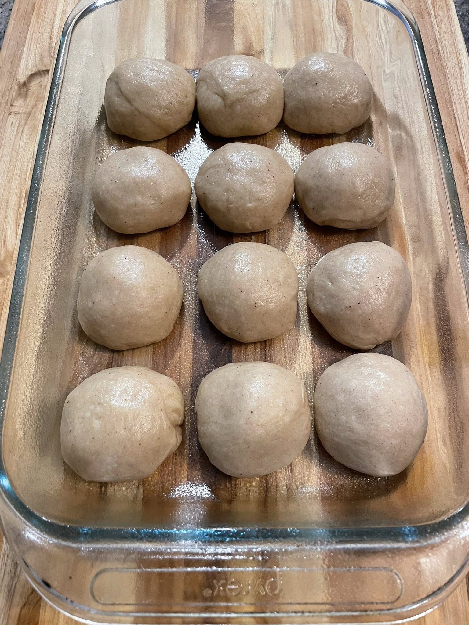 Spiced dough after first rise, smooth and domed in glass bowl.