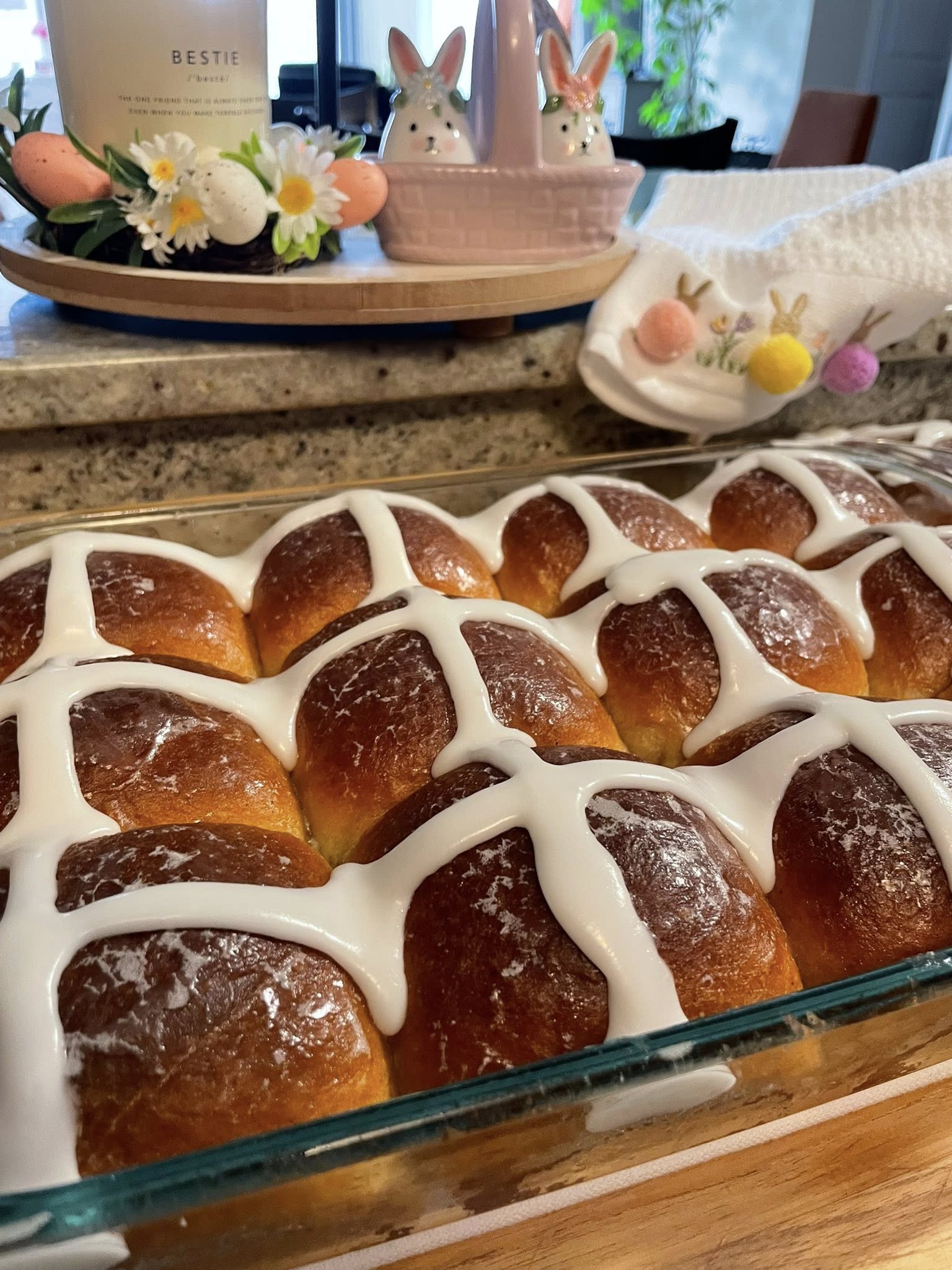Piping thick icing crosses over cooled buns.