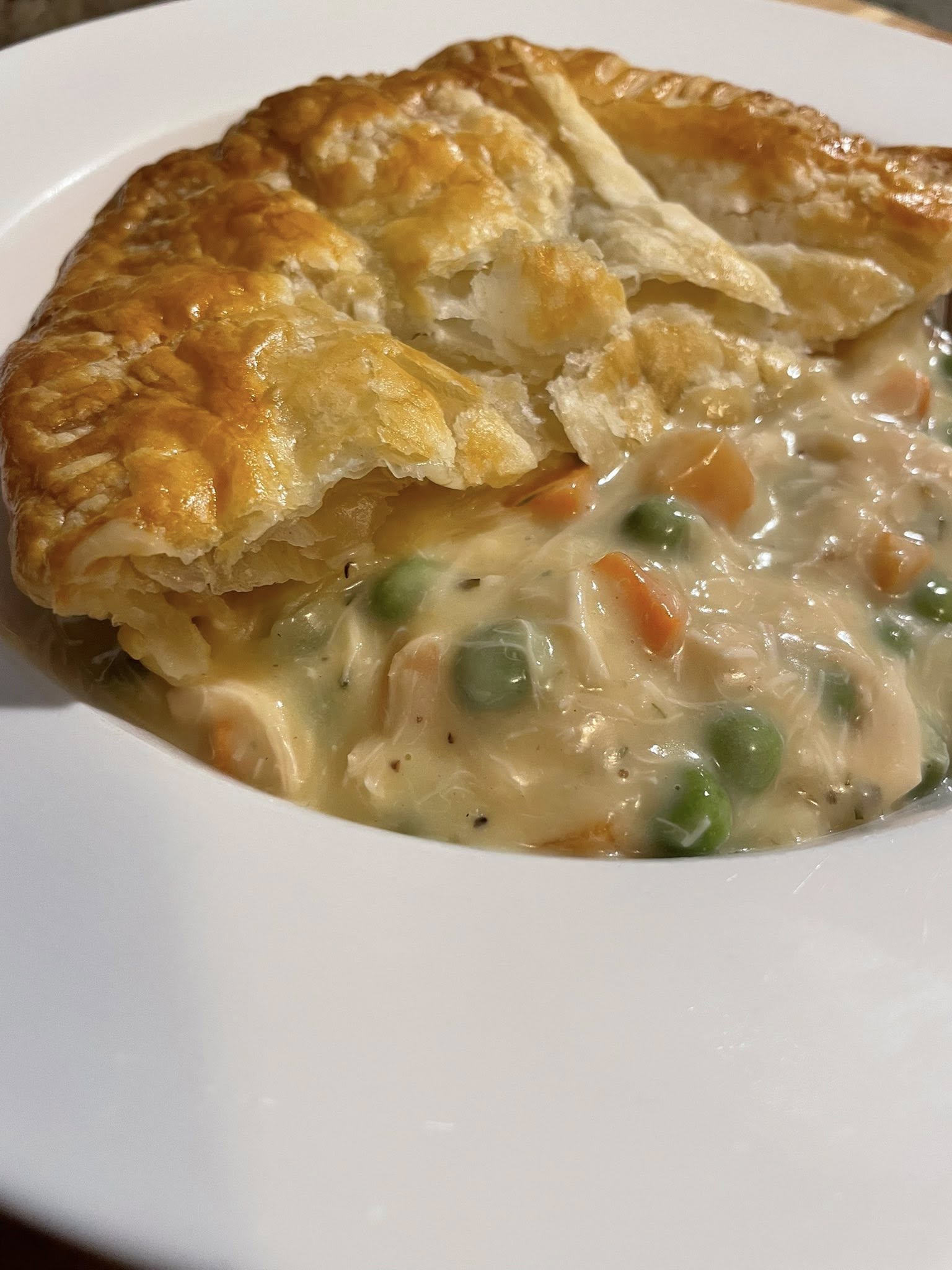  Serving home down chicken pot pie with puff pastry in white bowl with golden crust